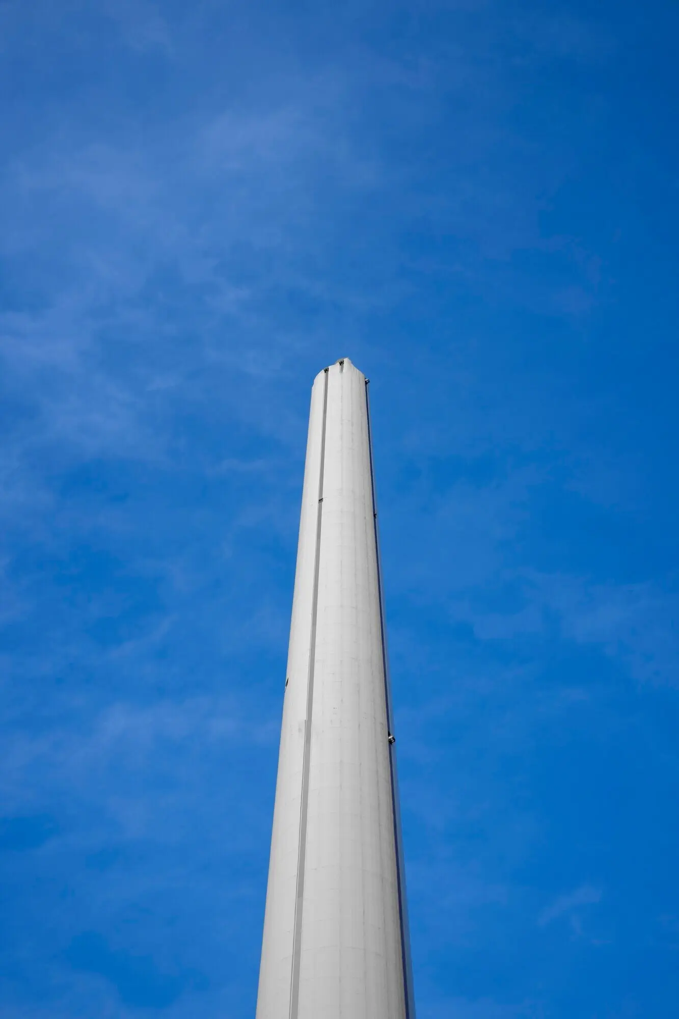 Low-angle view of a tall chimney against a blue sky.
