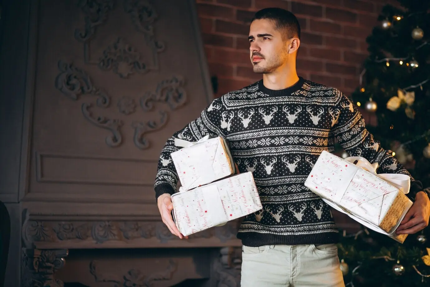 A handsome man carrying Christmas gifts.