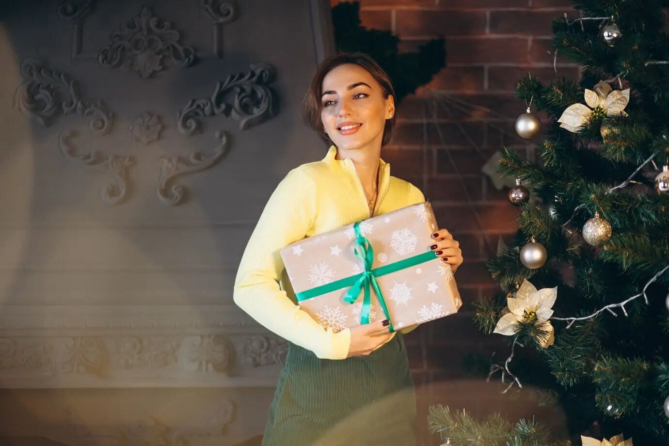 A woman unwrapping presents next to a Christmas tree.