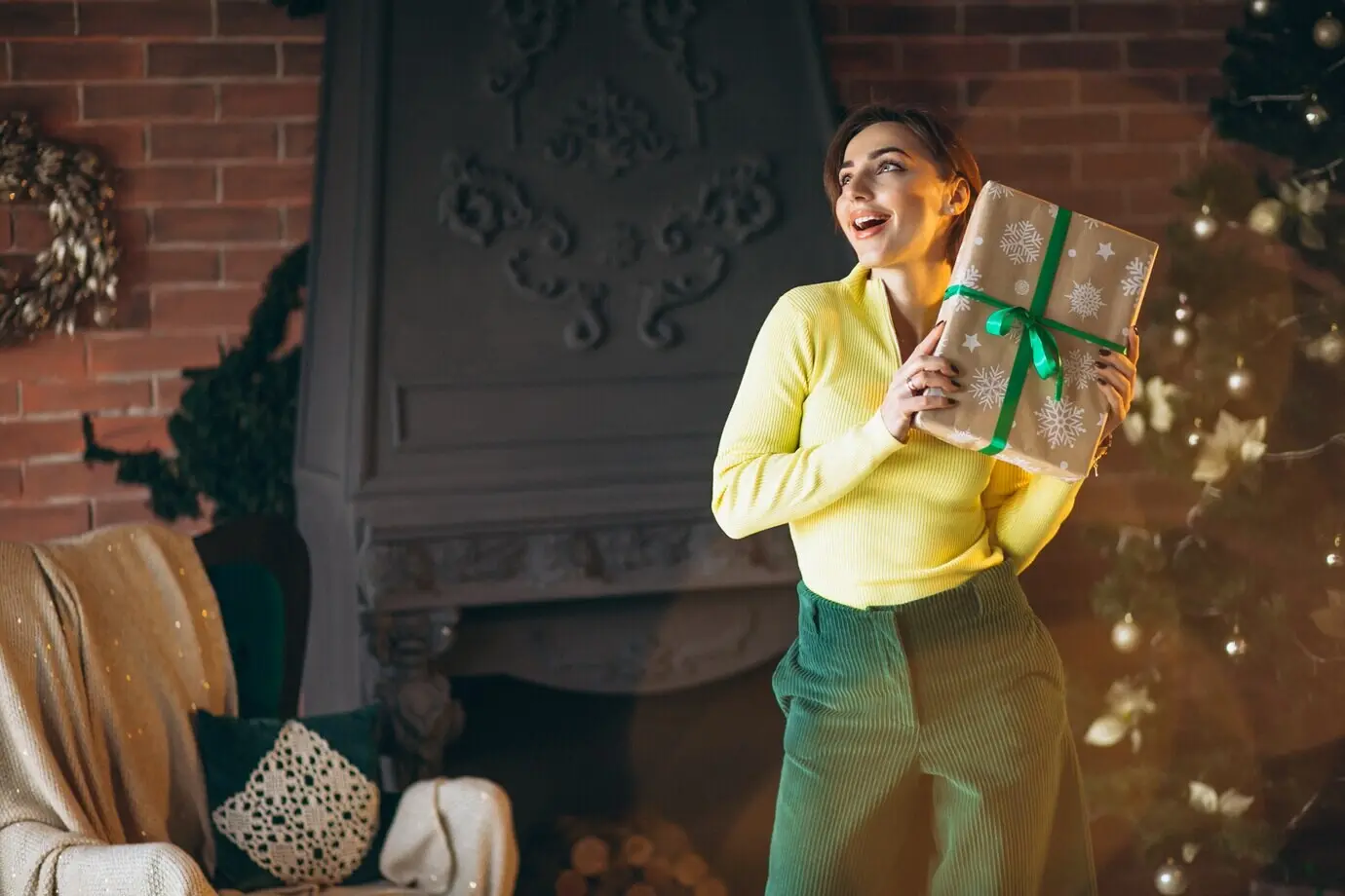 A woman opening presents beside a Christmas tree.